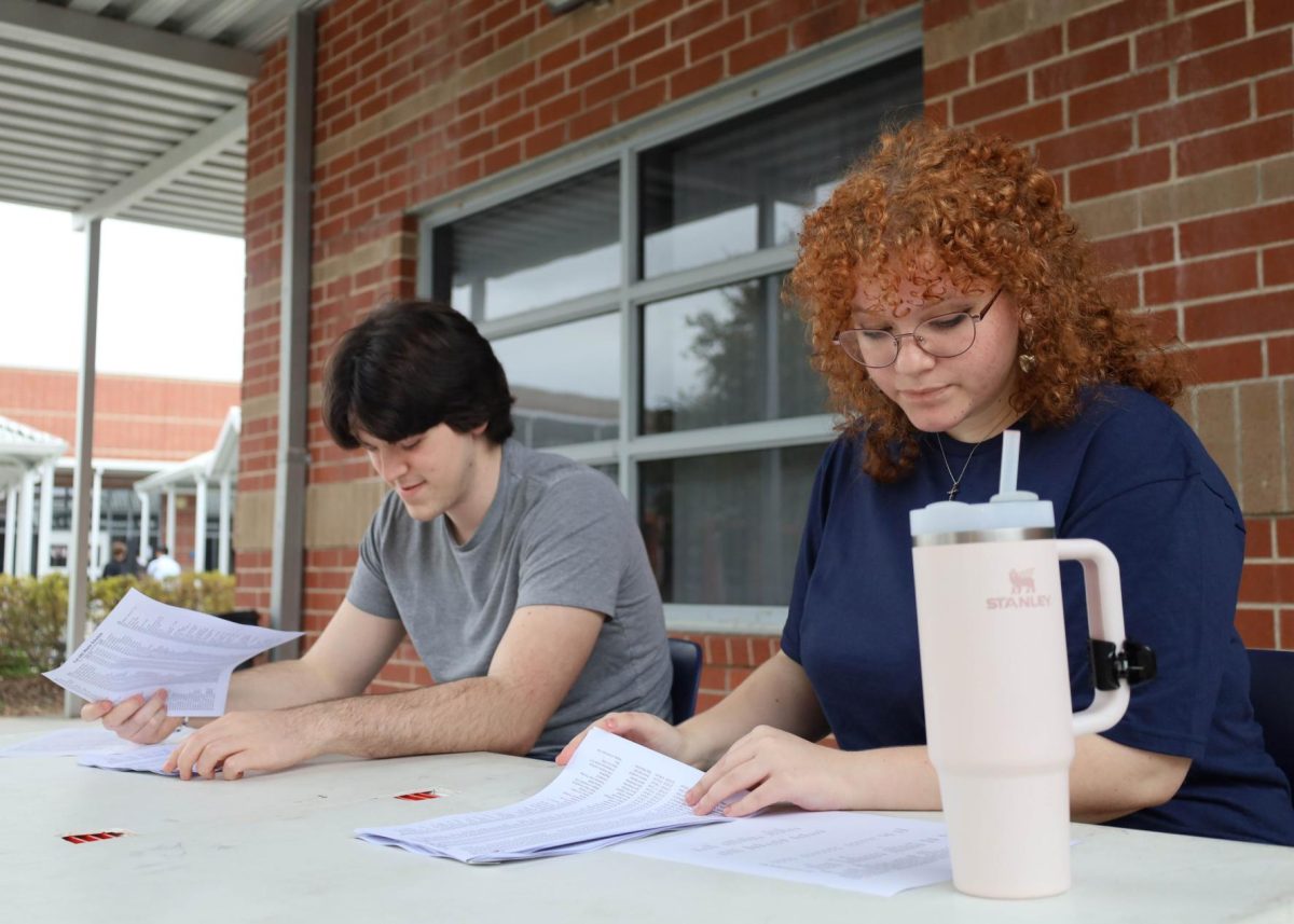 Junior Ava Sims and senior Samuel Joyner work at the check-in near the school's entrance. Members of the Tri-M honor society set up for Solo and Ensemble, then greeted participants and provided information at the check-in.