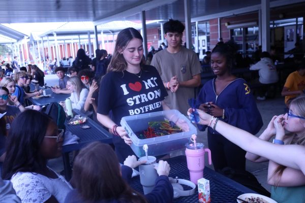 Senior Celine Merlin hands out heart-shaped sunglasses to students wearing "I ♥" shirts during second lunch.