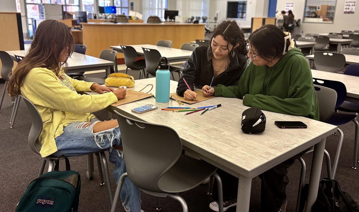 Junior Camila Kruega and friends decorate paper bags with flowers. Students were provided with bags as well as markers and colored pencils.