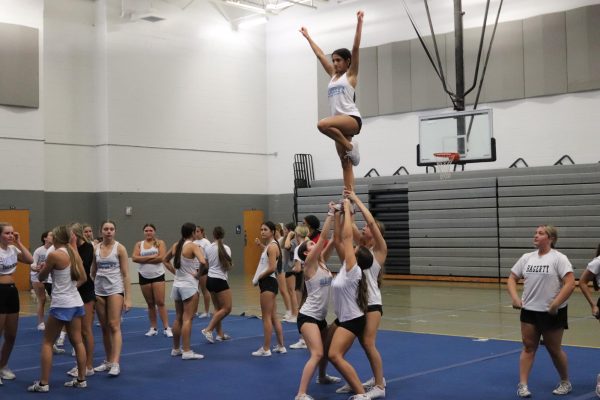 The cheer team practices stunts in the school gym. They practice for competitions and football games three times a week. 