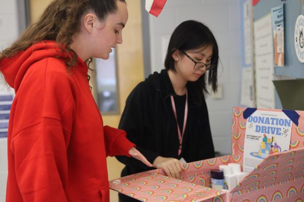 Co-presidents Maeryn Jacob and Helen Pan organize the donations box to Zebra Youth. Students can donate to the drive by bringing hygiene products to room 7-209.