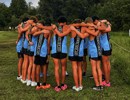 The boys cross-country team huddles before the race. The team came in first place at the annual Spikes and Spurs meet. Photo by Jay Getty