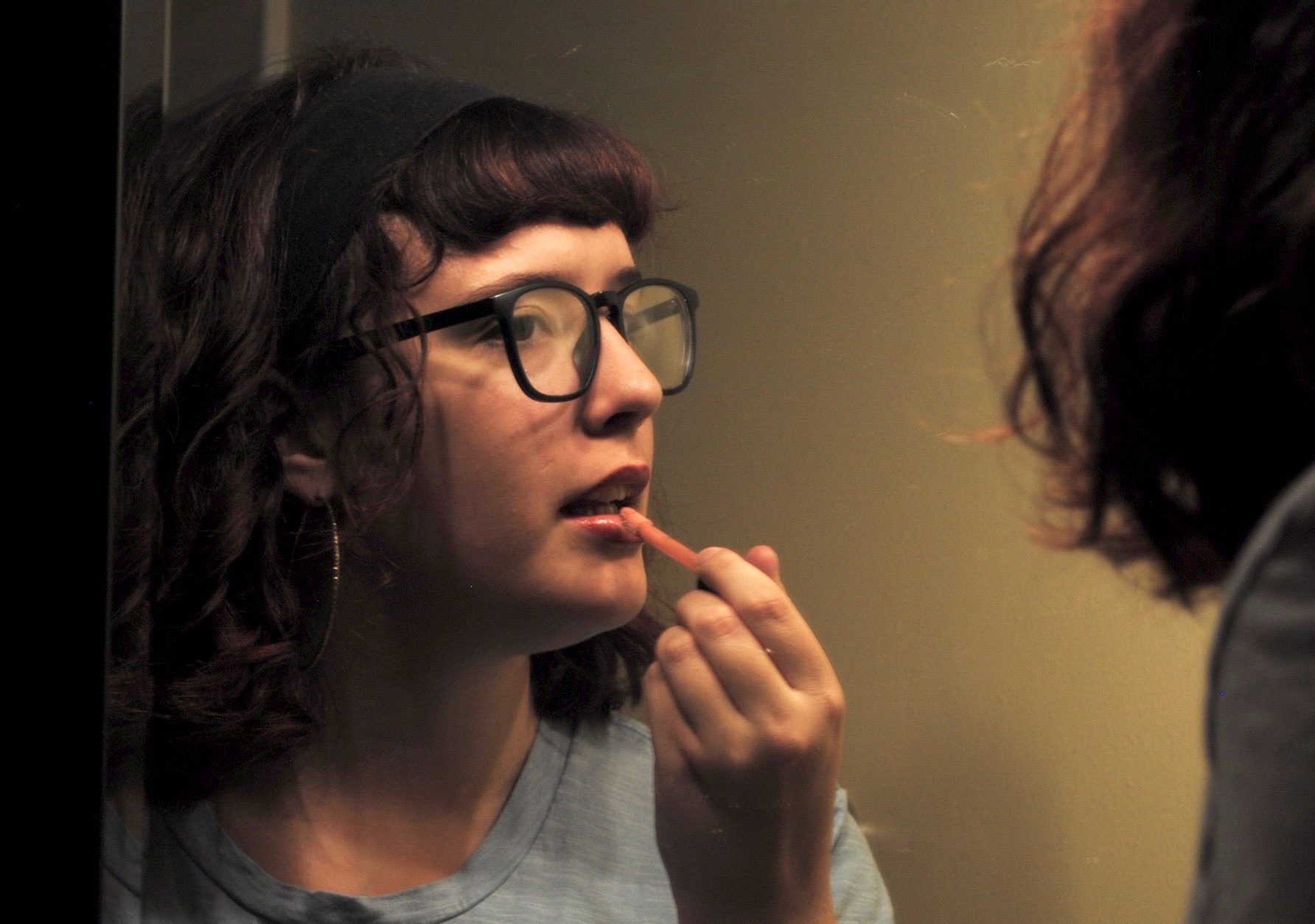 Sophomore Lily Karr applies lip gloss at her vanity. Many girls on campus wear makeup to boost their confidence. Shot on Nikon D3000.
