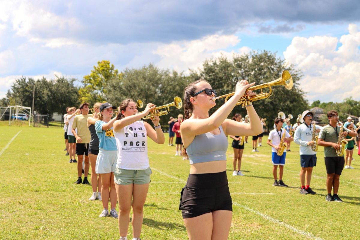 Senior Maeryn Jacob blasts her trumpet on the practice field as a band rehearsal continues after school.