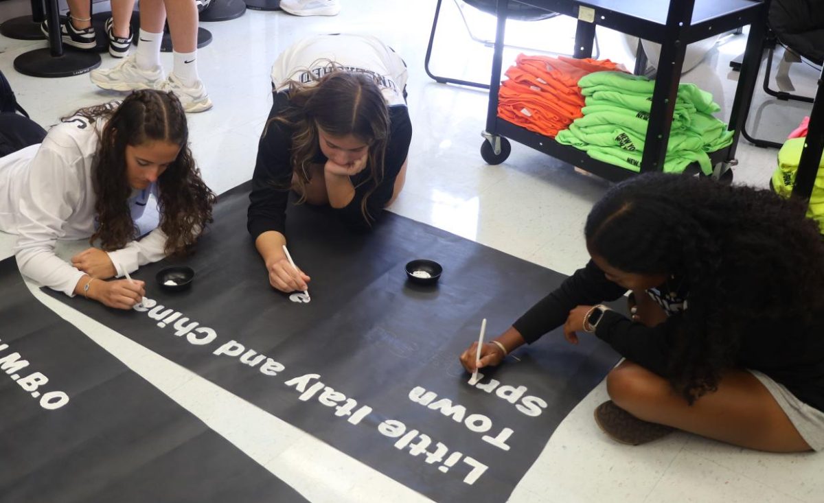 Leadership team members Norah Ford, Kira Saint-Jean and Marie Morris work on Homecoming posters for the campus.