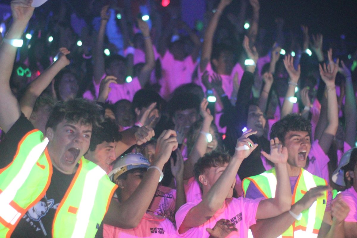 The senior section cheers during the Neon Pep Rally. The pep rally, which took place during Homecoming Week, reflected an increase in school spirit. (Photo by Lucas Franco)