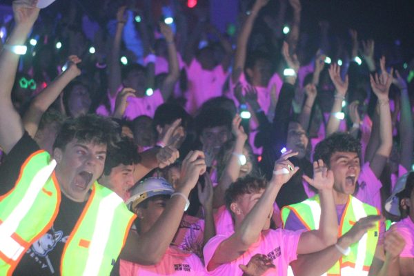 The senior section cheers during the Neon Pep Rally. The pep rally, which took place during Homecoming Week, reflected an increase in school spirit. (Photo by Lucas Franco)