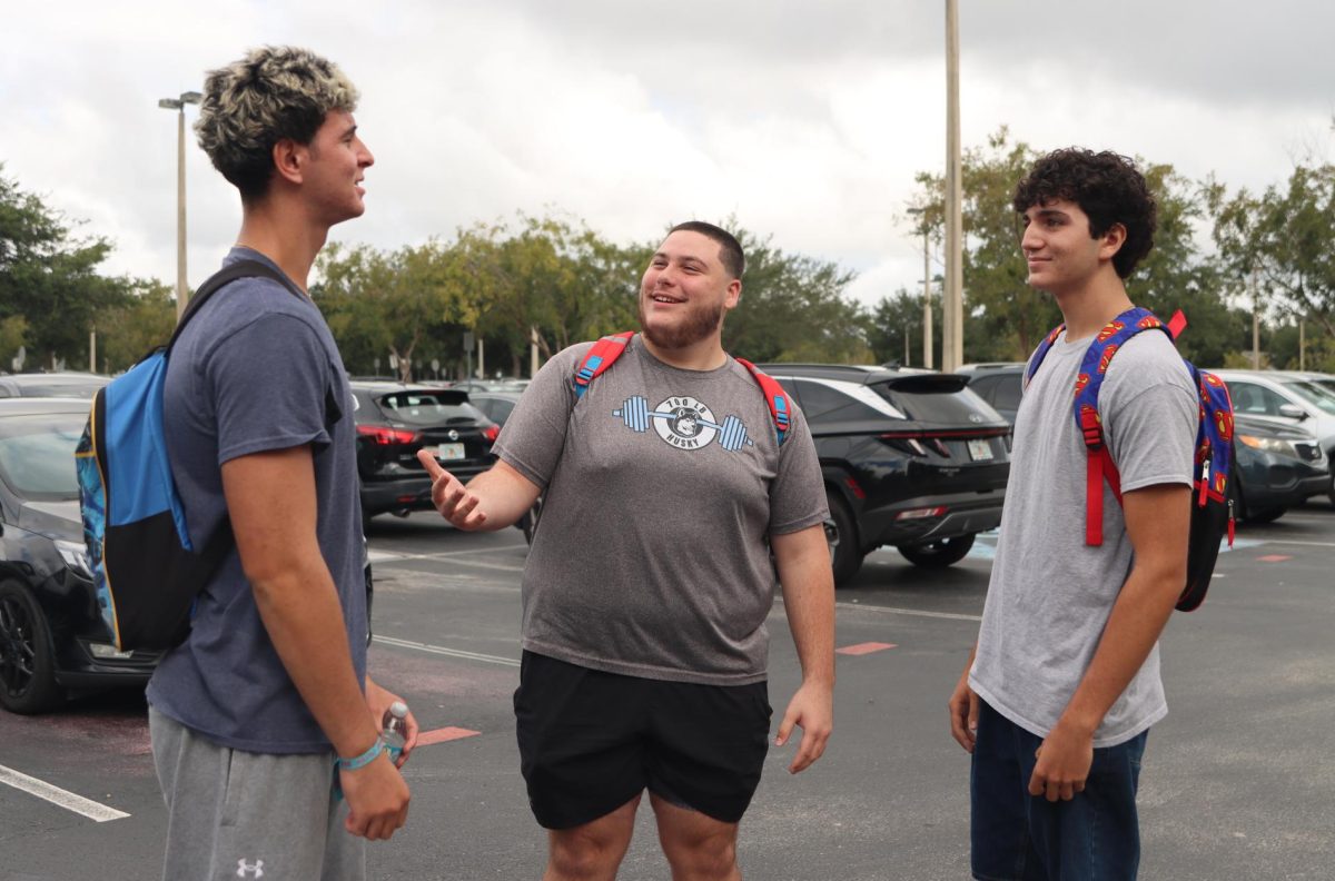 Seniors Noah Danos, David Pollack, and Dylan Allocca chat in the parking lot after leaving school. This illustrates the trend of upperclassman taking periods off and leaving earlier in the day.