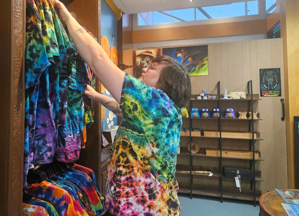 Wizards and Lizards owner Adam Brown organizes tie dye shirts in his shop. Brown has seen the Oviedo Mall change over years of doing business.