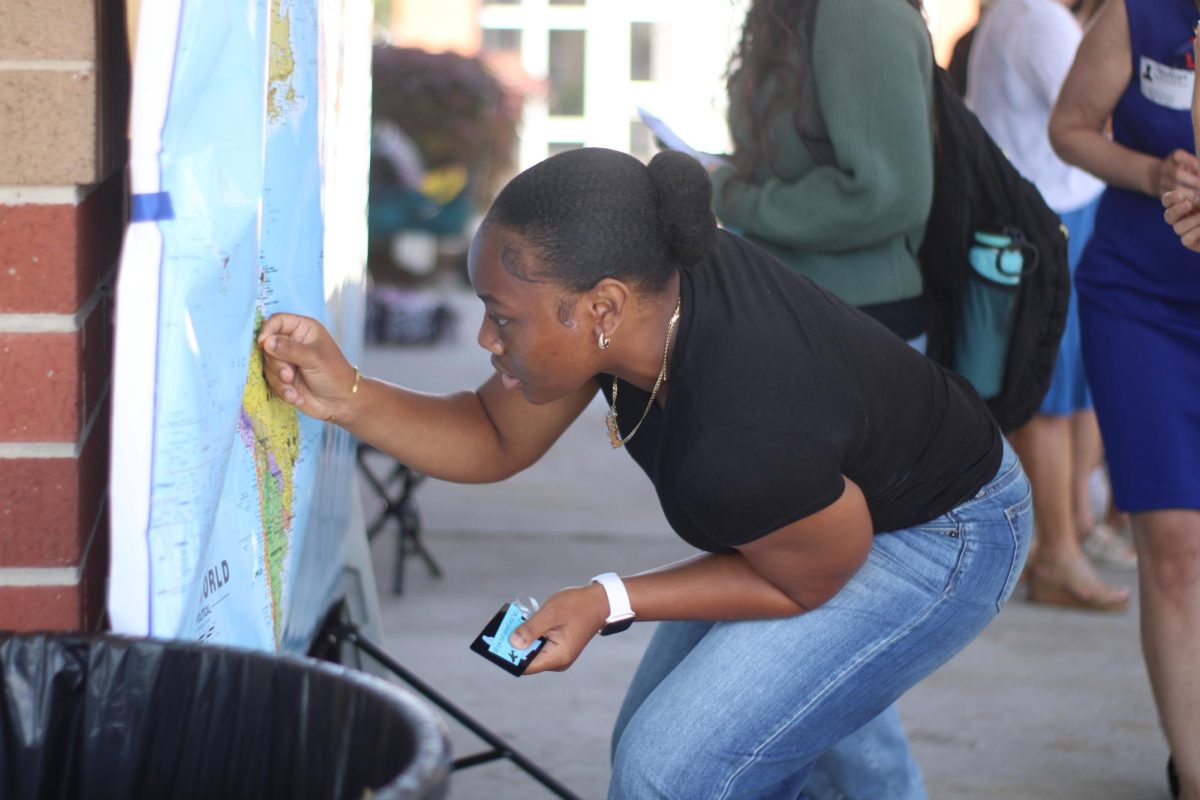 A senior places a sticker on a world map during the "10 years forward" dress-up day. During lunch, parents set up a giant map display and encouraged students to indicate the location they hoped to be in 10 years.