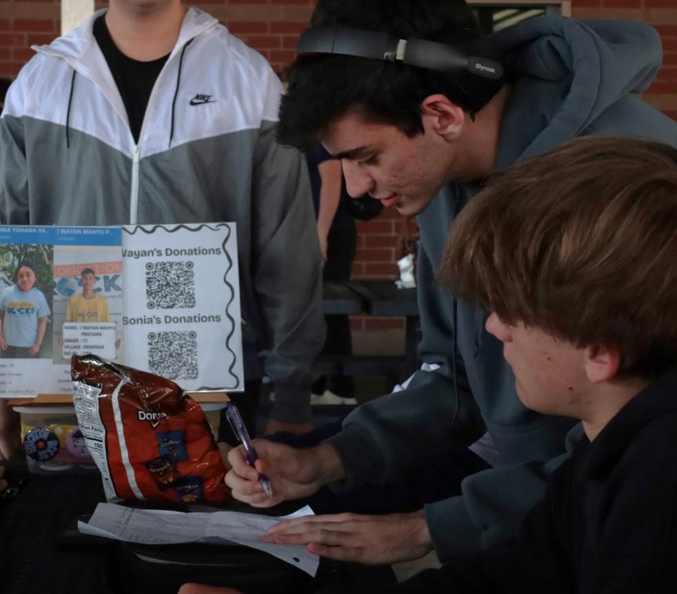Senior Vinicius Lopes de Mattos signs up to give donations while senior Luciano Burd looks on. Donations go to students in developing countries to help them gain an education. 