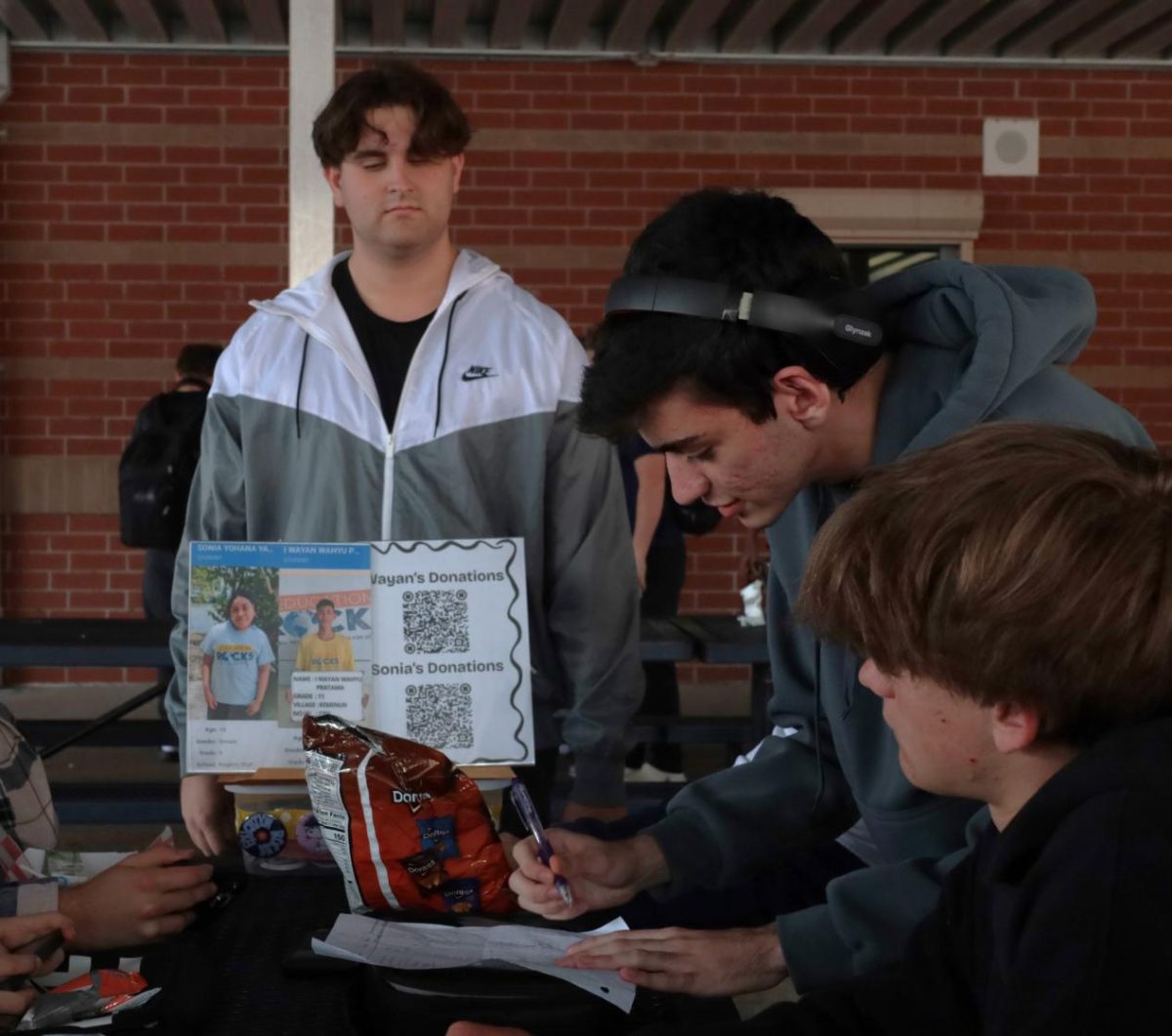 Senior Vinicius Lopes de Mattos signs up to give donations while senior Luciano Burd looks on. Donations go to students in developing countries to help them gain an education. 