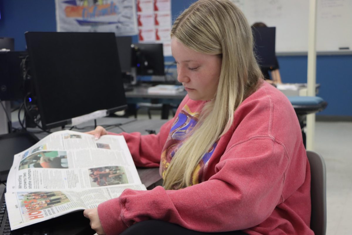 Junior Avery Chegg reads the latest print issue. Currently, Foundations of Journalism is learning about newspaper designs.