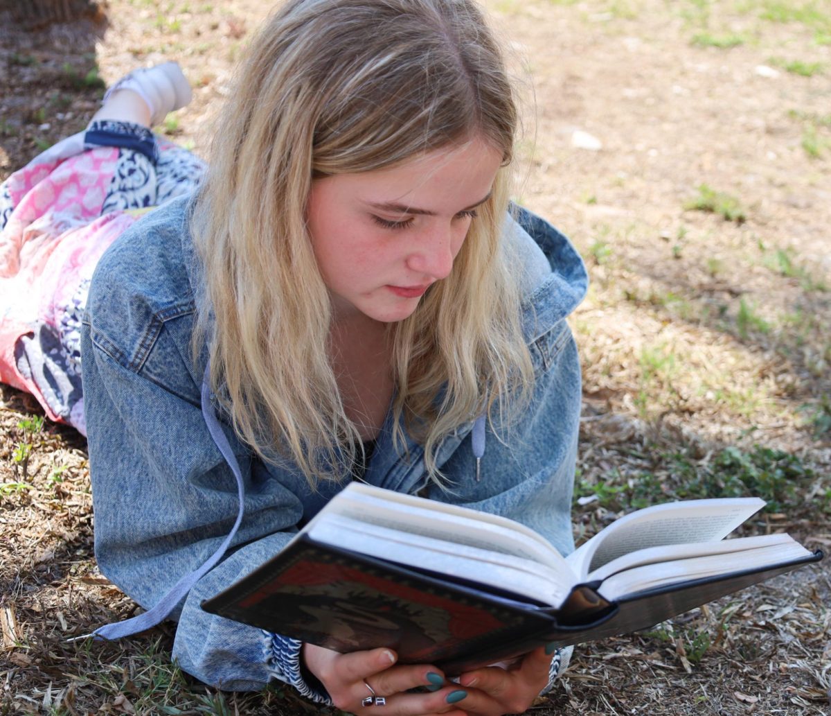 Sophomore Lucy Garbelman lays on the grass and reads. With the temperature becoming warmer and summer on the way, many students have found time to read outdoors.