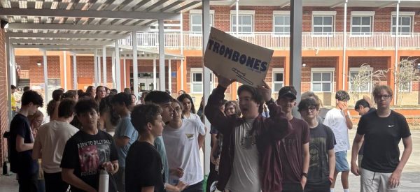 Sophomore John Watson holds up the trombone sign to gather up his section. With the chaos of incoming and current members, it is hard to keep everyone together. Photo by Caityln Shaffer
